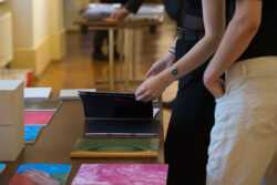 Personen, die Fotobücher der Ausstellungseröffnung Fotografie Ortweinschule 2022 in der Fotogalerie im Grazer Rathaus ansehen